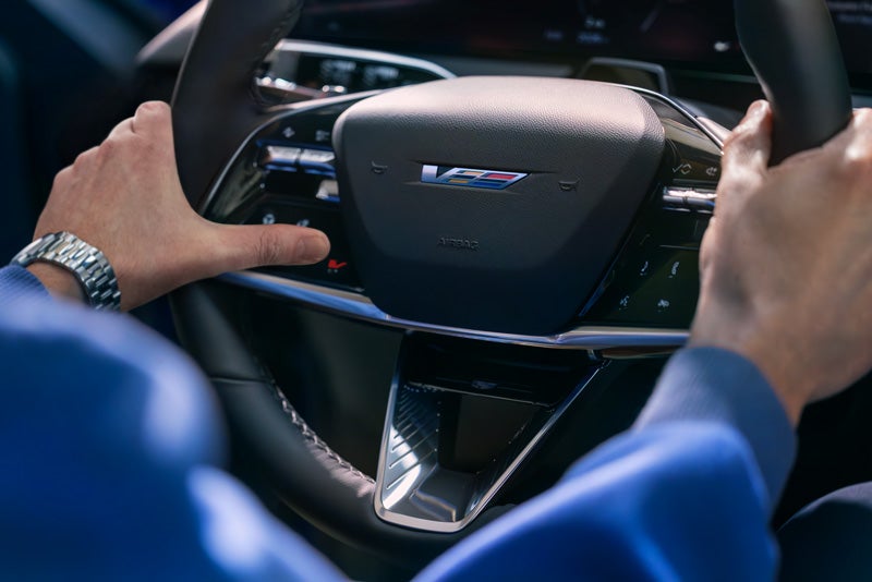Close-up of a Man About to Press the V-Button on the 2026 OPTIQ-V Steering Wheel | Bomnin Cadillac Homestead in Homestead FL