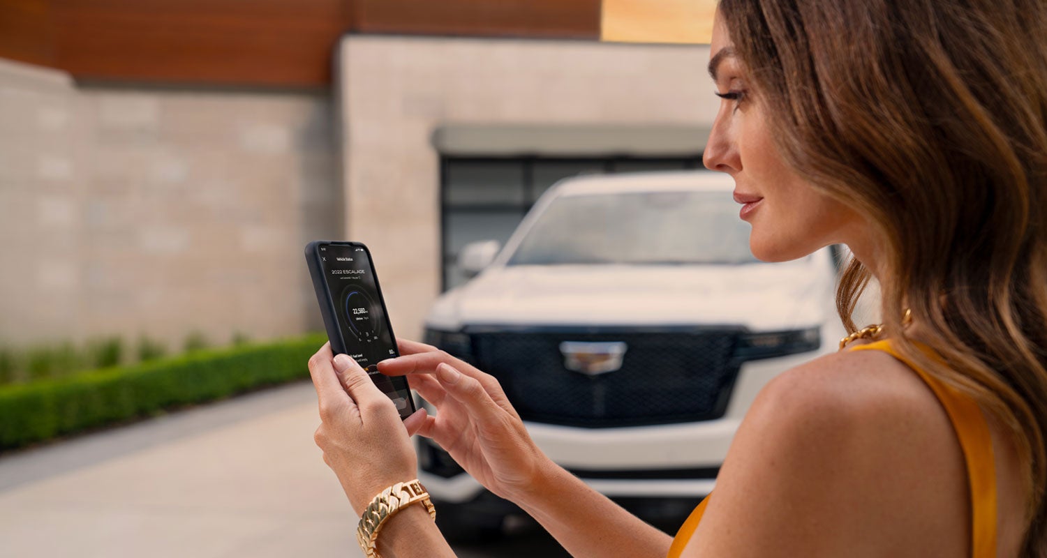 lady checking her mobile with a Cadillac vehicle background | Bomnin Cadillac Homestead in Homestead FL